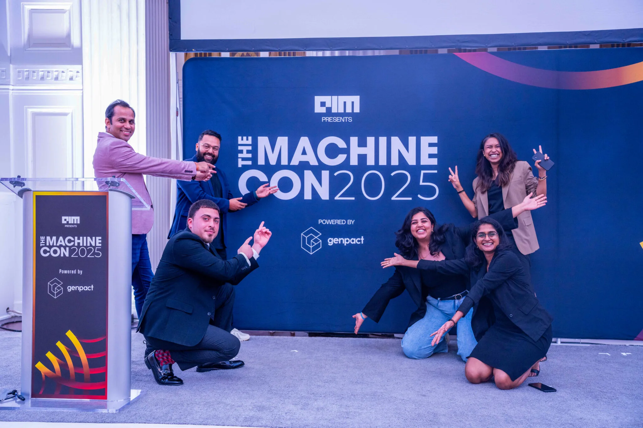 Group posing in front of banner at MachineCon New York 2025