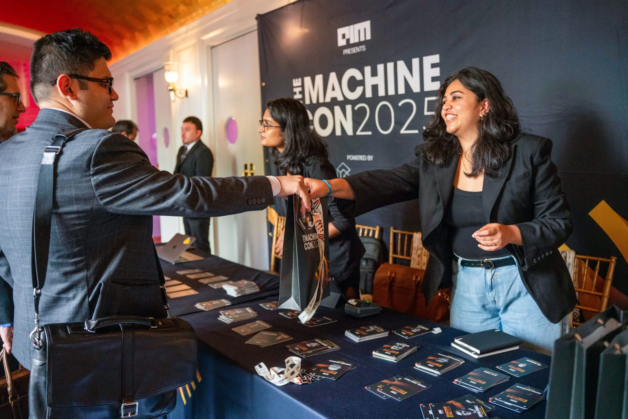 Exchanging event materials at registration at MachineCon New York 2025